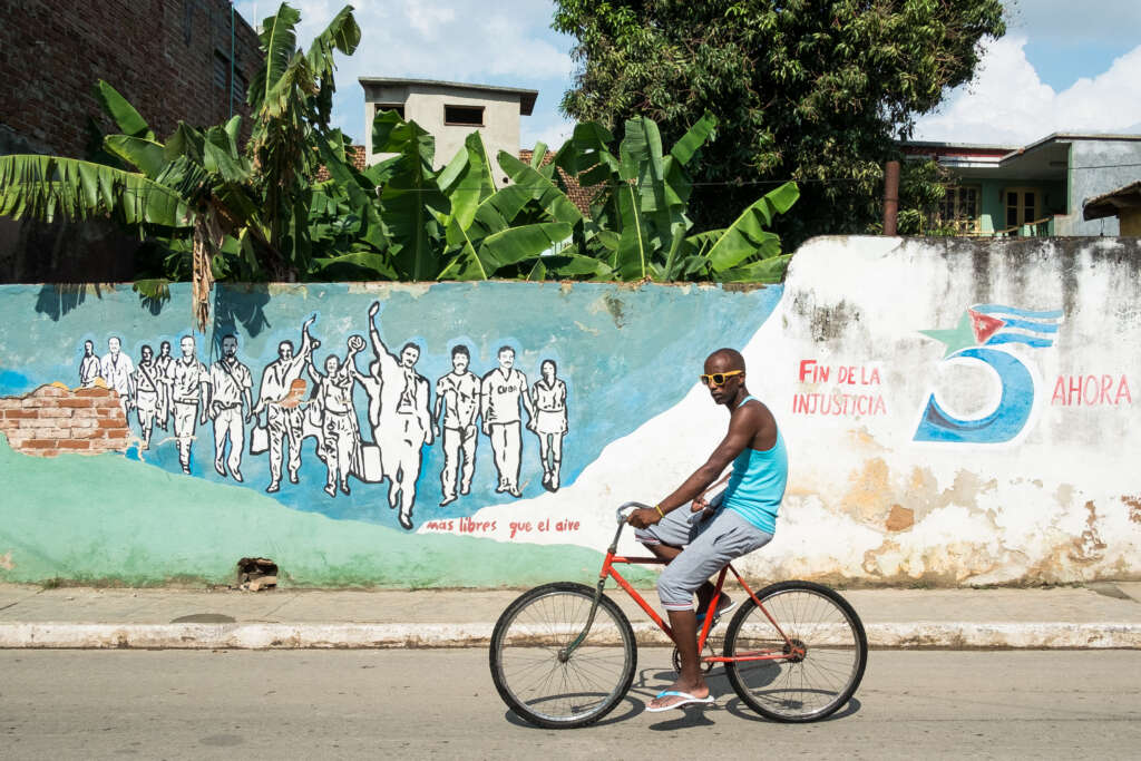Fahrradfahrer mit Sonnenbrille vor Mauer - Ein Foto aus Kuba von Journalist, Fotograf und GATE7 Podcaster Kai Behrmann - bei uns zu Gast im Heimatlichter-Podcast