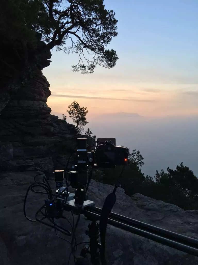 Kamera auf einem Slider und mit Verlaufsfilter ausgestattet steht an einem Aussichtspunkt im Pfälzerwald und nimmt einen Zeitraffer / Timelapse auf.