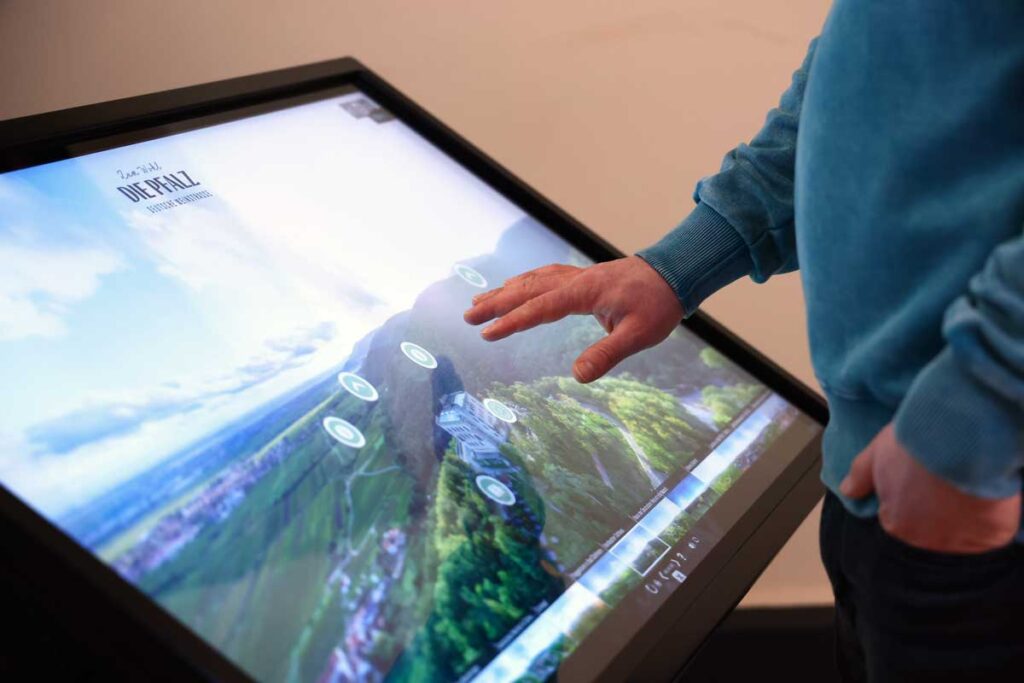 Ein Mann schaut sich die 360°-Pfalz Tour auf einem Touchscreen in der Touristinformation Maikammer an